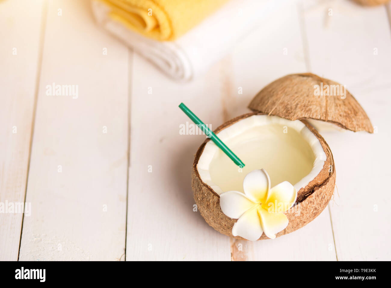 Noce di cocco e frutta spa accessori con caffè naturale scrub, bianco e giallo asciugamani, conchiglie di mare, fiori esotici su sfondo di legno. Bellezza, spa trea Foto Stock