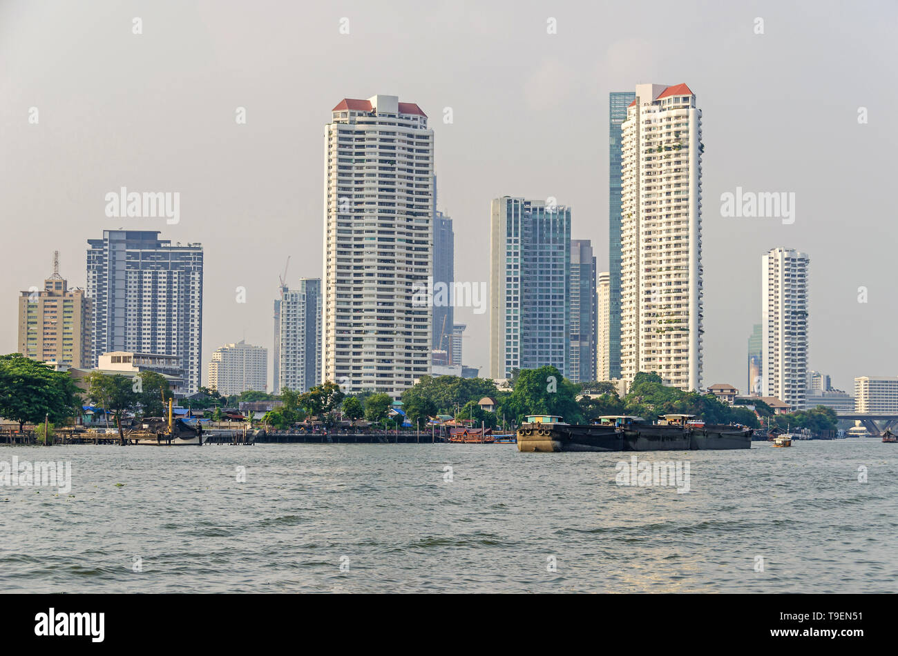 Bangkok, Tailandia - 18 Aprile 2018: Skyline presso le rive del Fiume Chao Phraya con barche e i suoi moderni edifici vicino al ponte Taksin Foto Stock