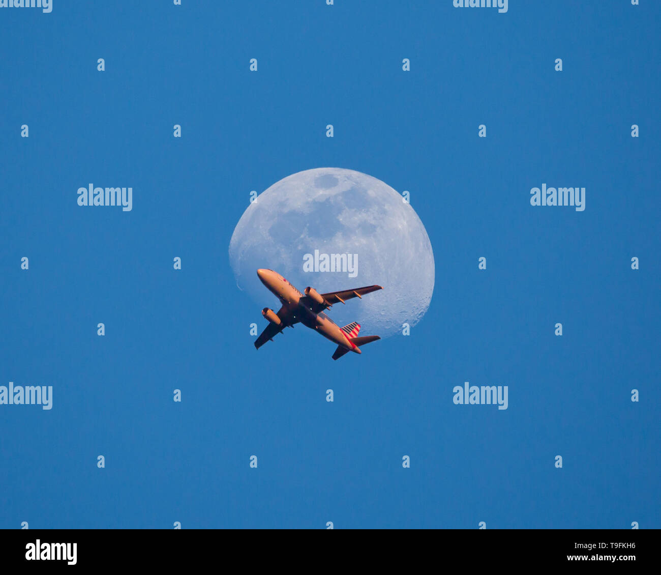 Un aereo commerciale passa davanti alla luna al tramonto poco dopo il decollo. Foto Stock