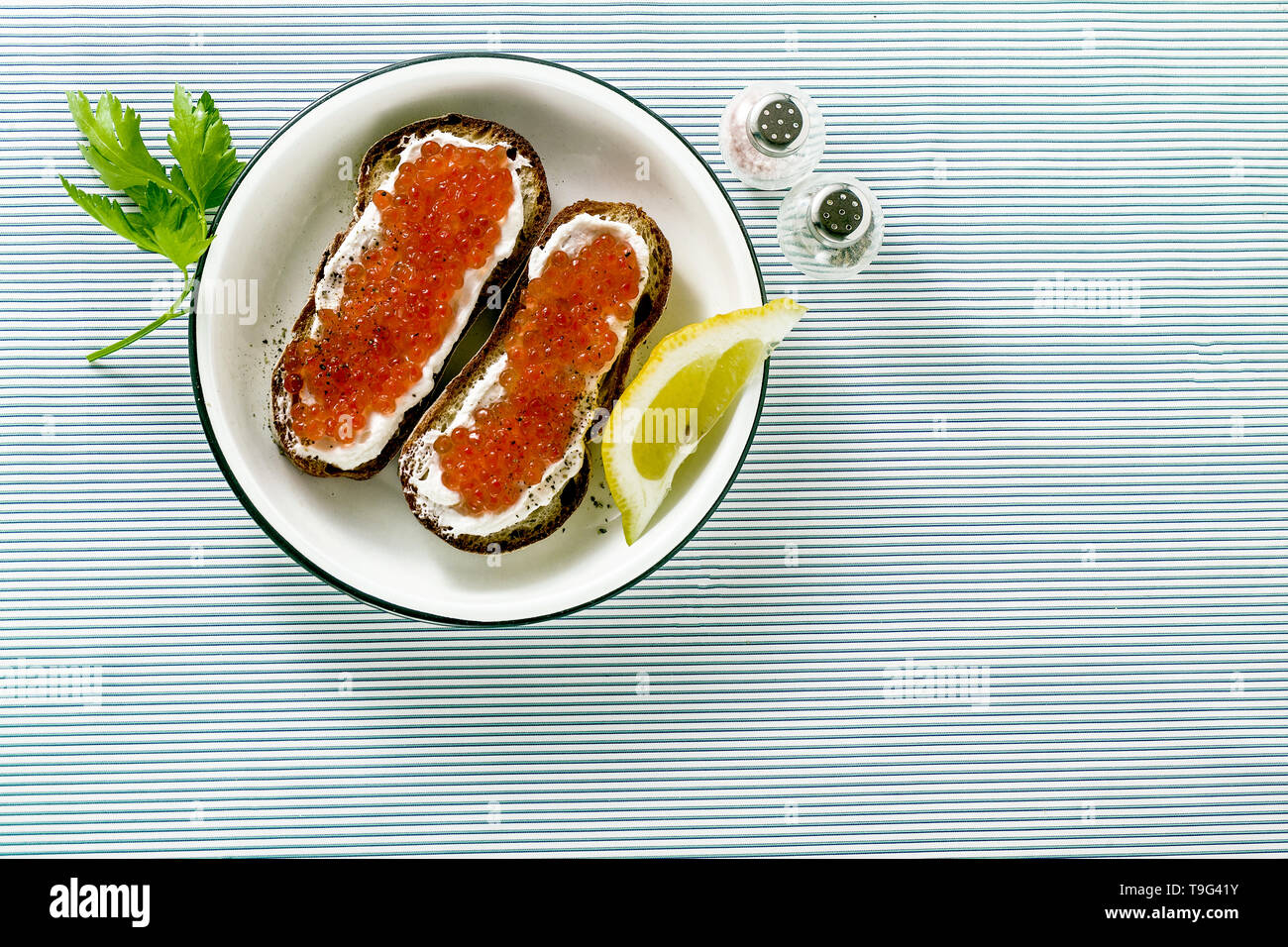 Pane fresco in sandwich con caviale rosso e formaggio morbido su una piastra. classica combinazione di ingredienti. snack sul tavolo Foto Stock