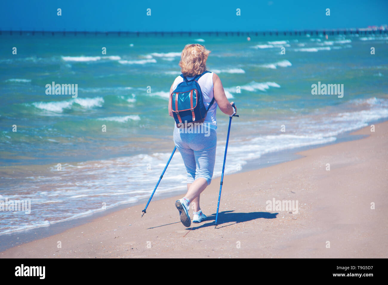 Una donna anziana praticare il Nordic walking sulla spiaggia Foto Stock