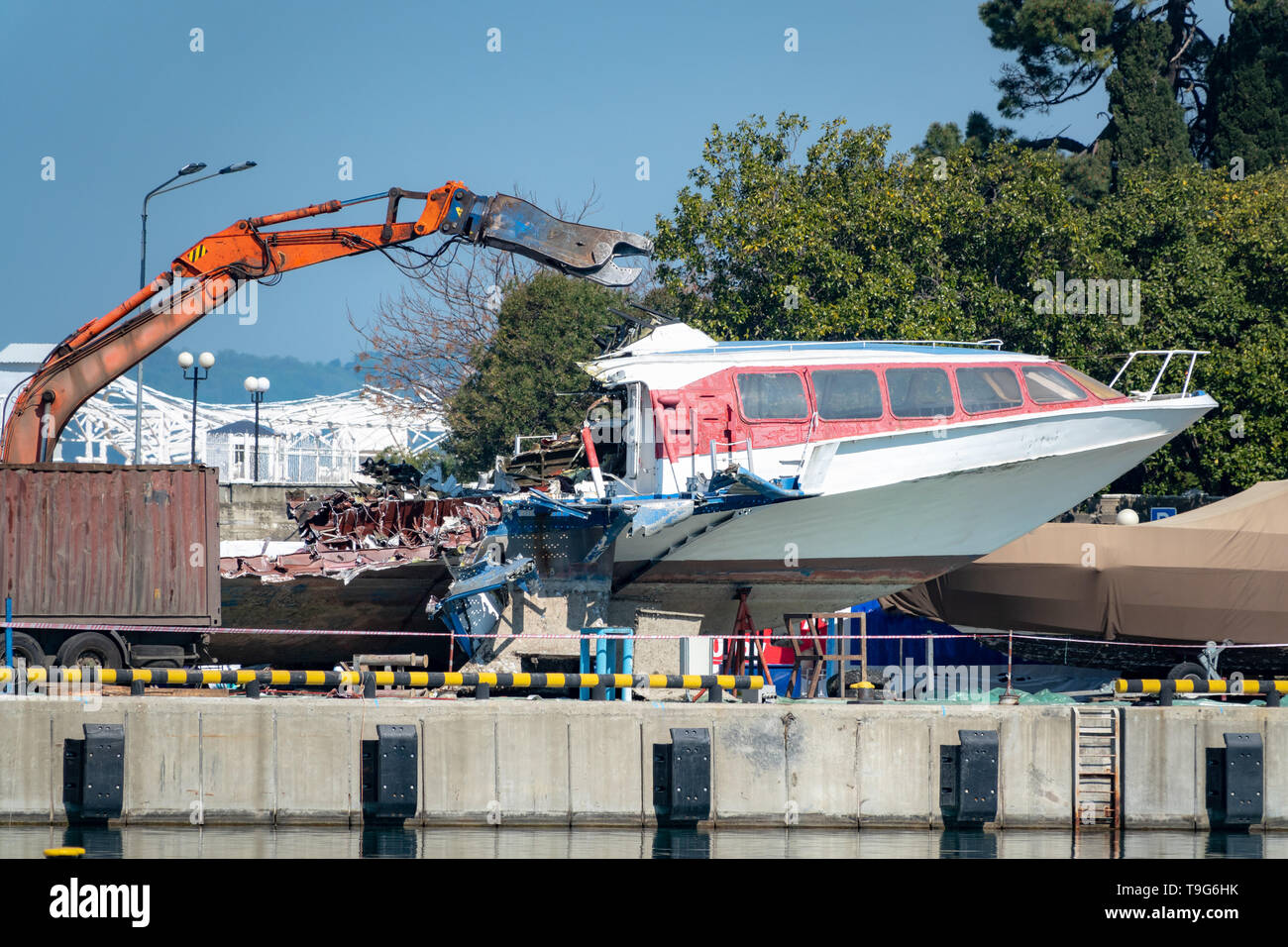 Escavatore idraulico con cesoia taglia un vecchio boat marine per il rottame. Smaltimento delle apparecchiature obsolete. Foto Stock