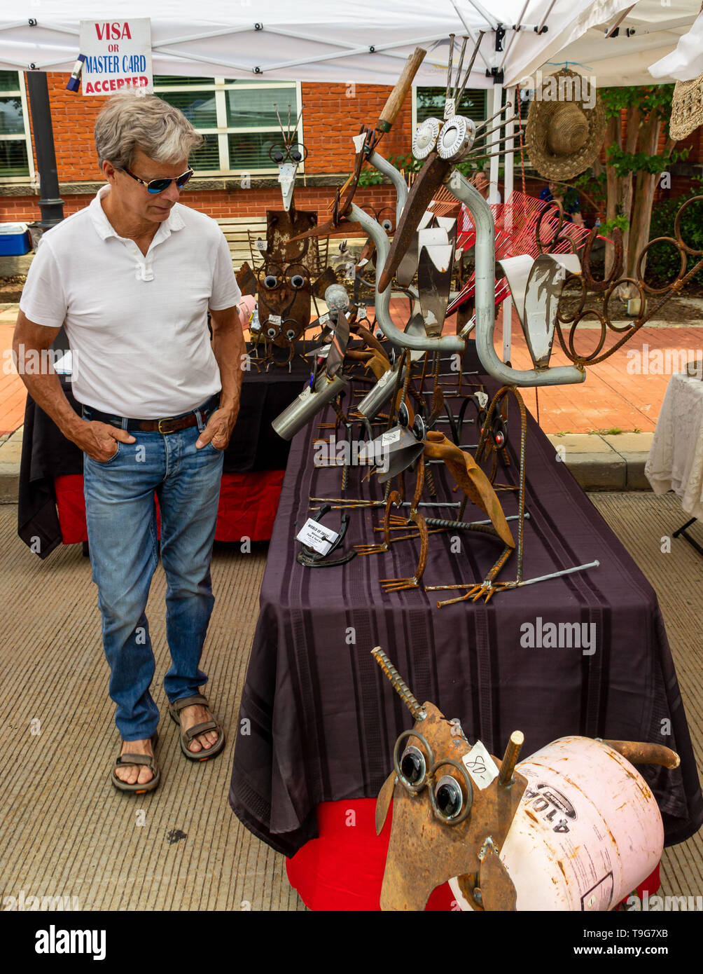 McDonough, Georgia - 18 Maggio 2019: un festival-goer guarda a sculture di metallo in corrispondenza di un venditore ambulante di stand annuale quarantaduesima Geranio Festival. Foto Stock