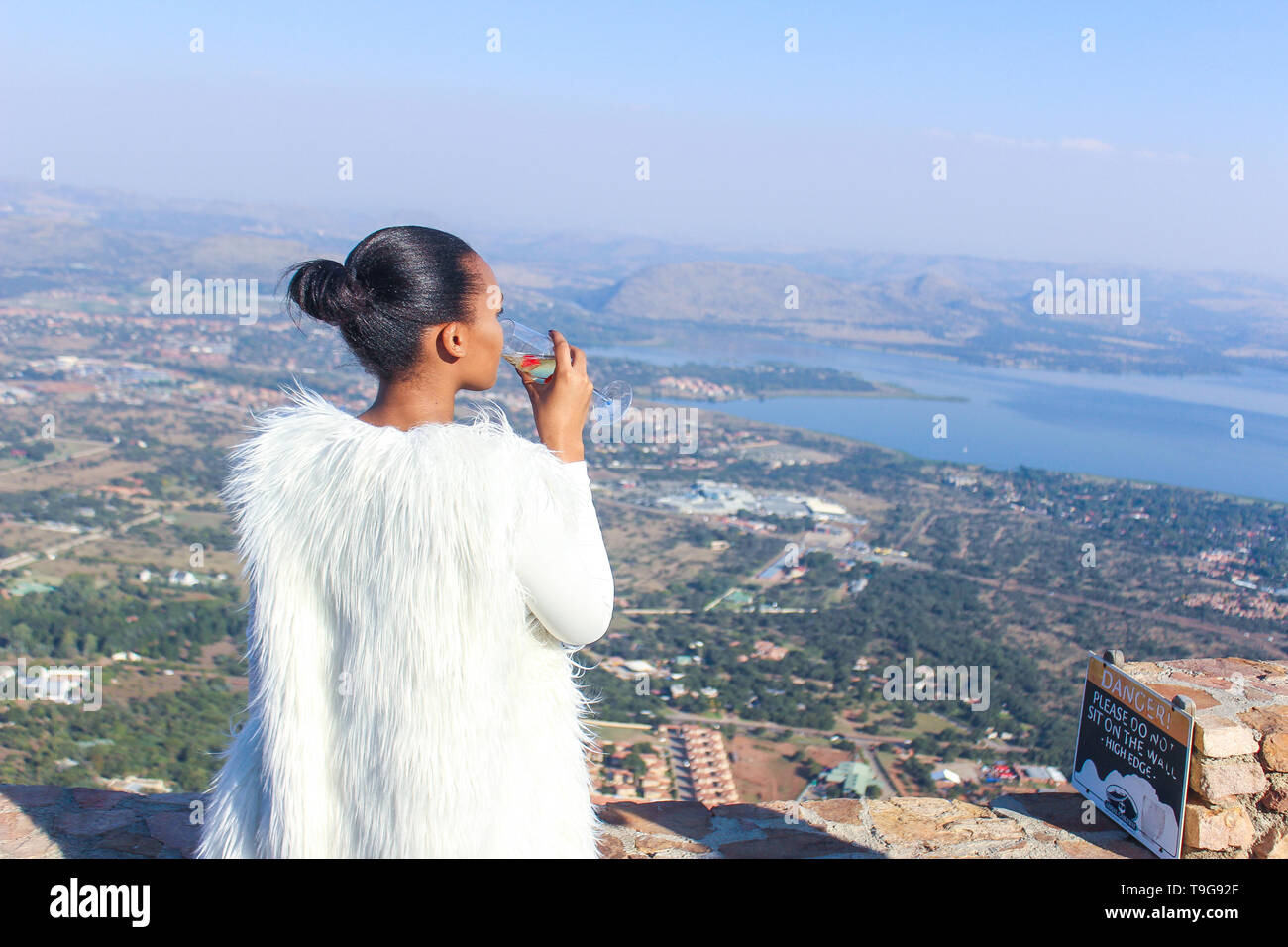 Una signora sorseggiando un bicchiere di vino su una splendida vista del paesaggio. Foto Stock