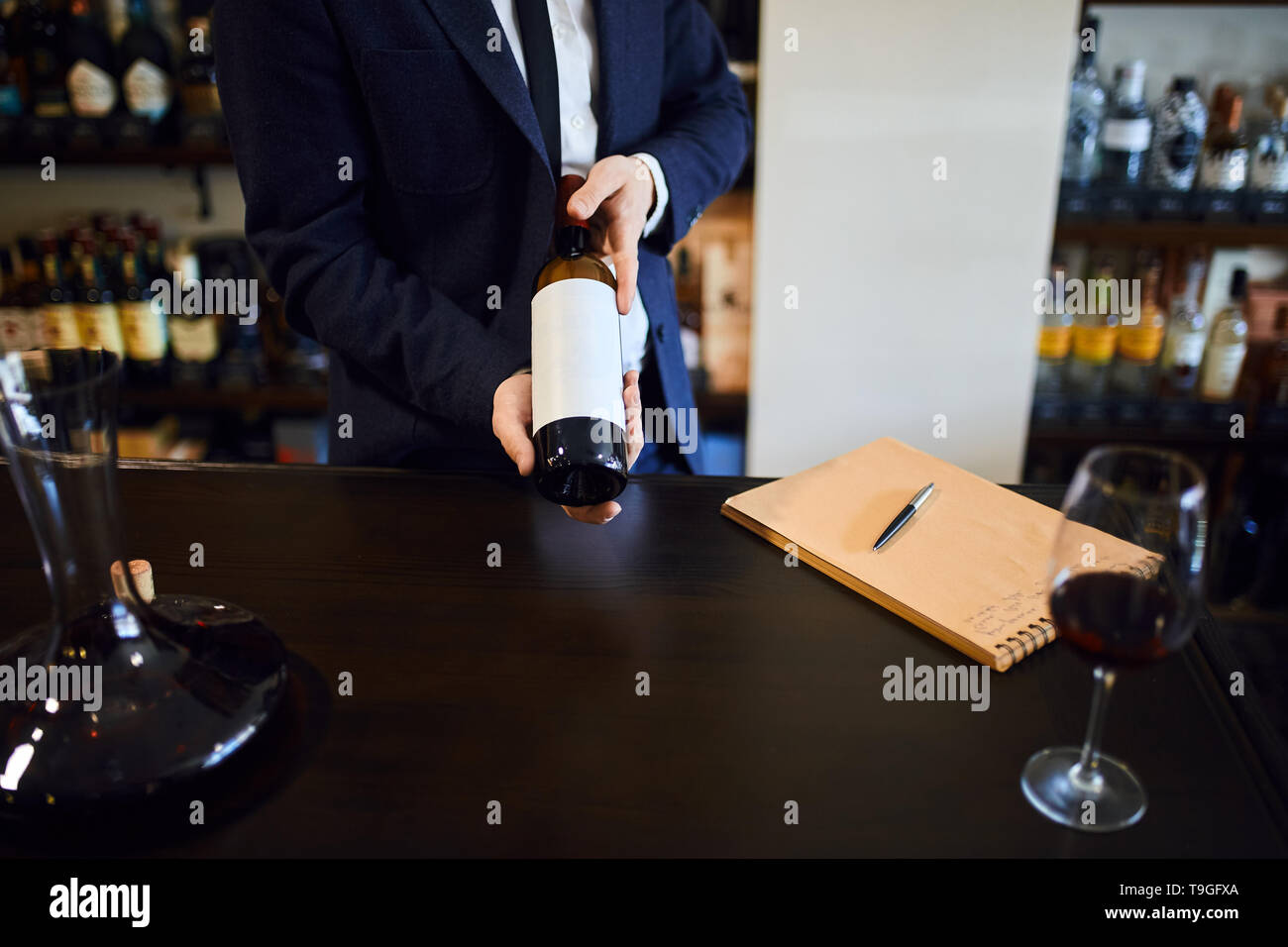Gli uomini in abiti formali tenendo un rosso Bottiglia di vino bianco con etichetta vuota di vino negozio o ristorante. close up foto ritagliata Foto Stock