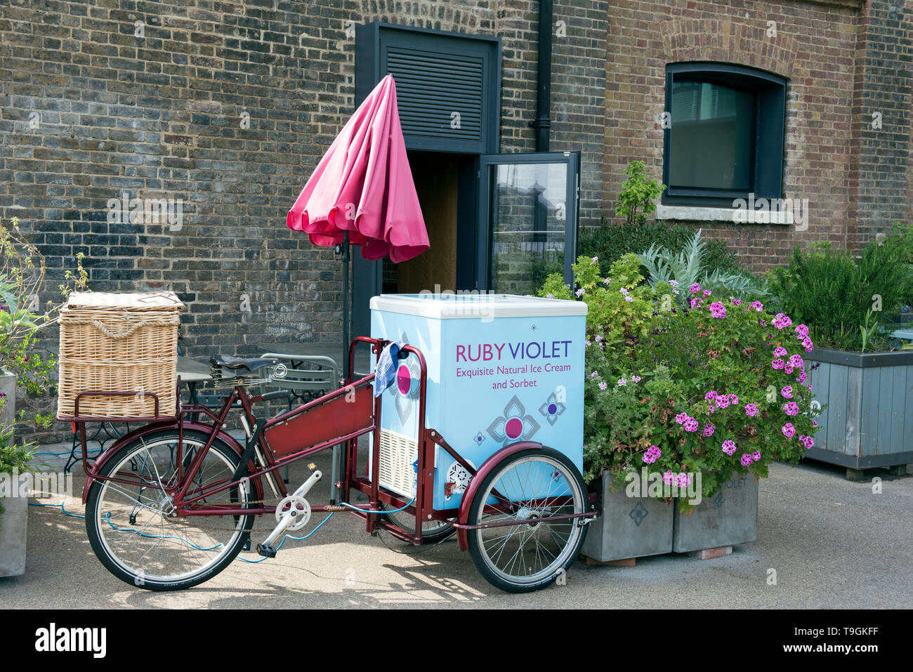 Ruby Violet Gelato bicicletta con ombrellone rosso accanto alle piantatrici nella parte anteriore del negozio Kings Cross Londra Inghilterra Gran Bretagna REGNO UNITO Foto Stock