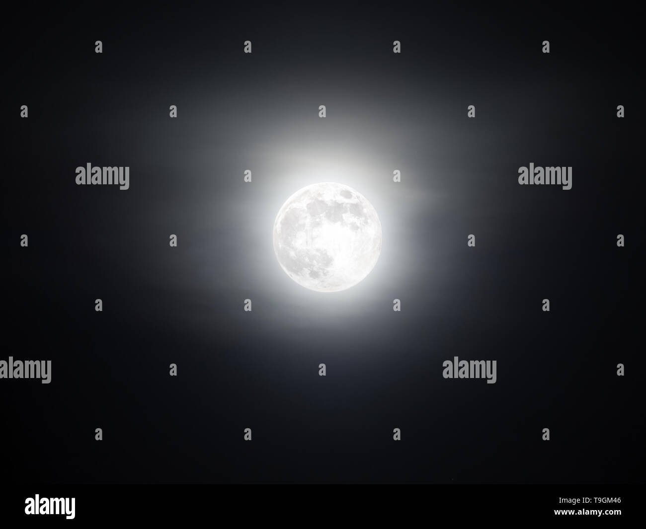 Foggy sky con la luminosa luna piena incandescente al buio Foto Stock