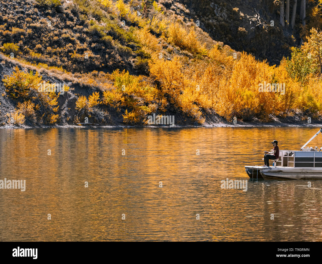 Incredibile paesaggio autunnale con il pescatore in un lago di montagna Foto Stock