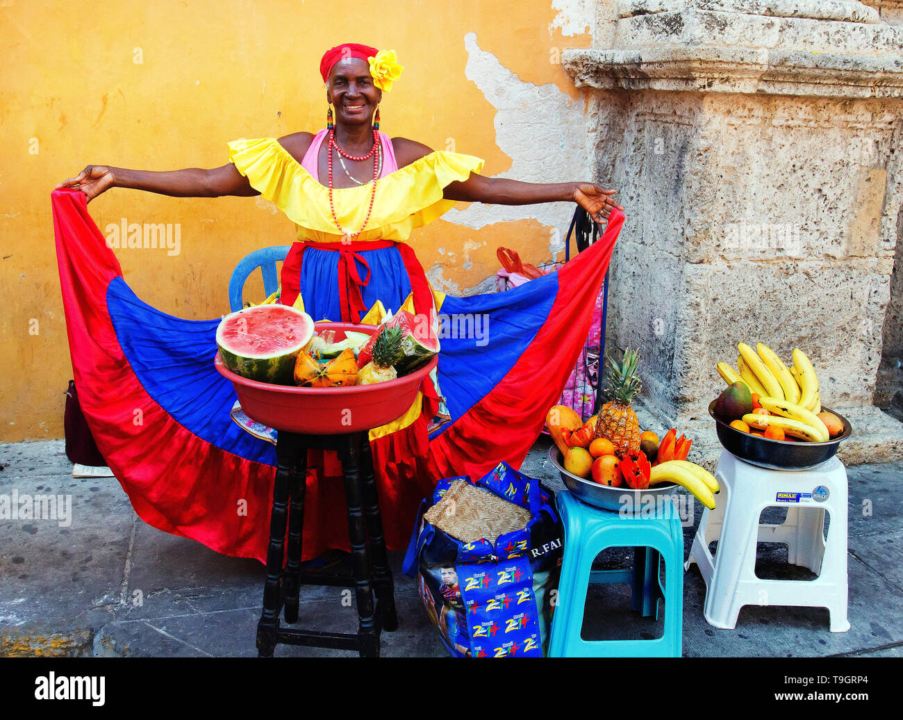 Gentile sorridente venditore di frutta in un abito colorato per la vendita di frutta sulla strada a Cartagena, Colombia Foto Stock