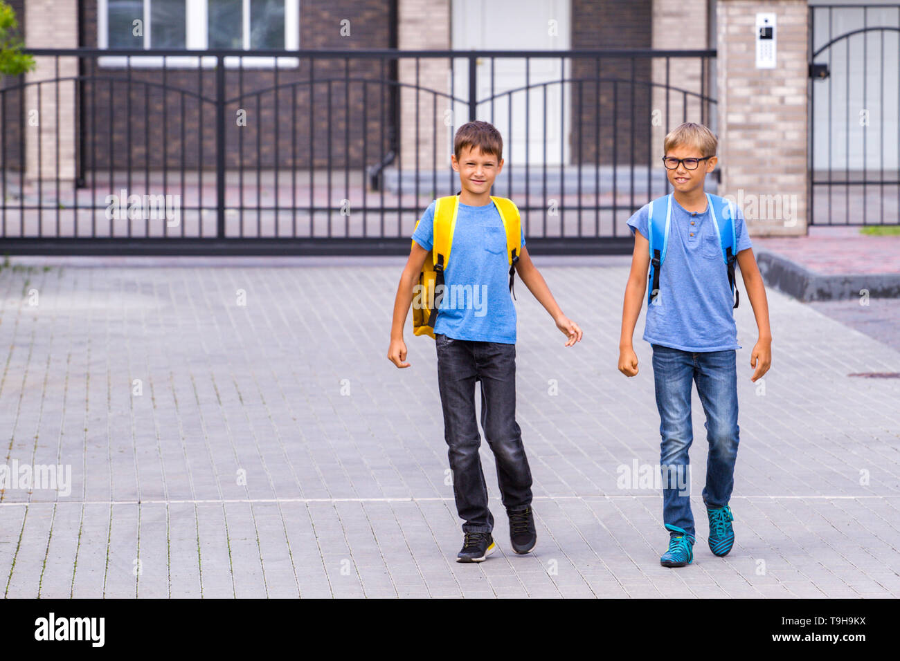 Due lieti shoolboys con zaini vai a scuola di mattina Foto Stock