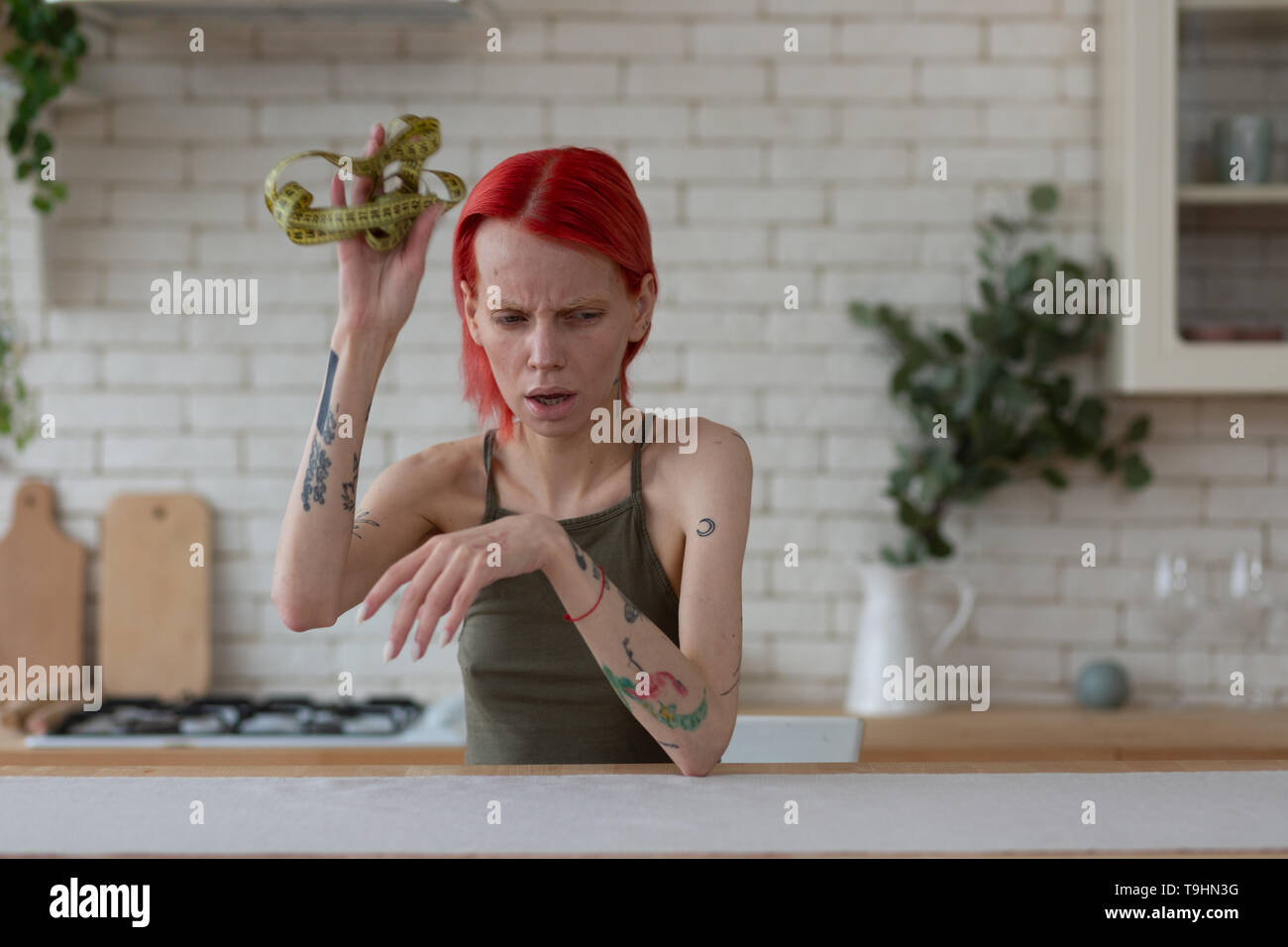 I capelli rossi anoressica donna gettando nastro di misurazione di distanza Foto Stock