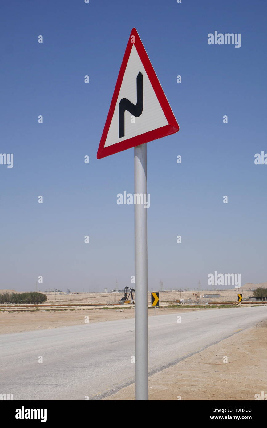 Cartello stradale sulle strade del deserto che mostra si piega in avanti, Regno del Bahrein Foto Stock