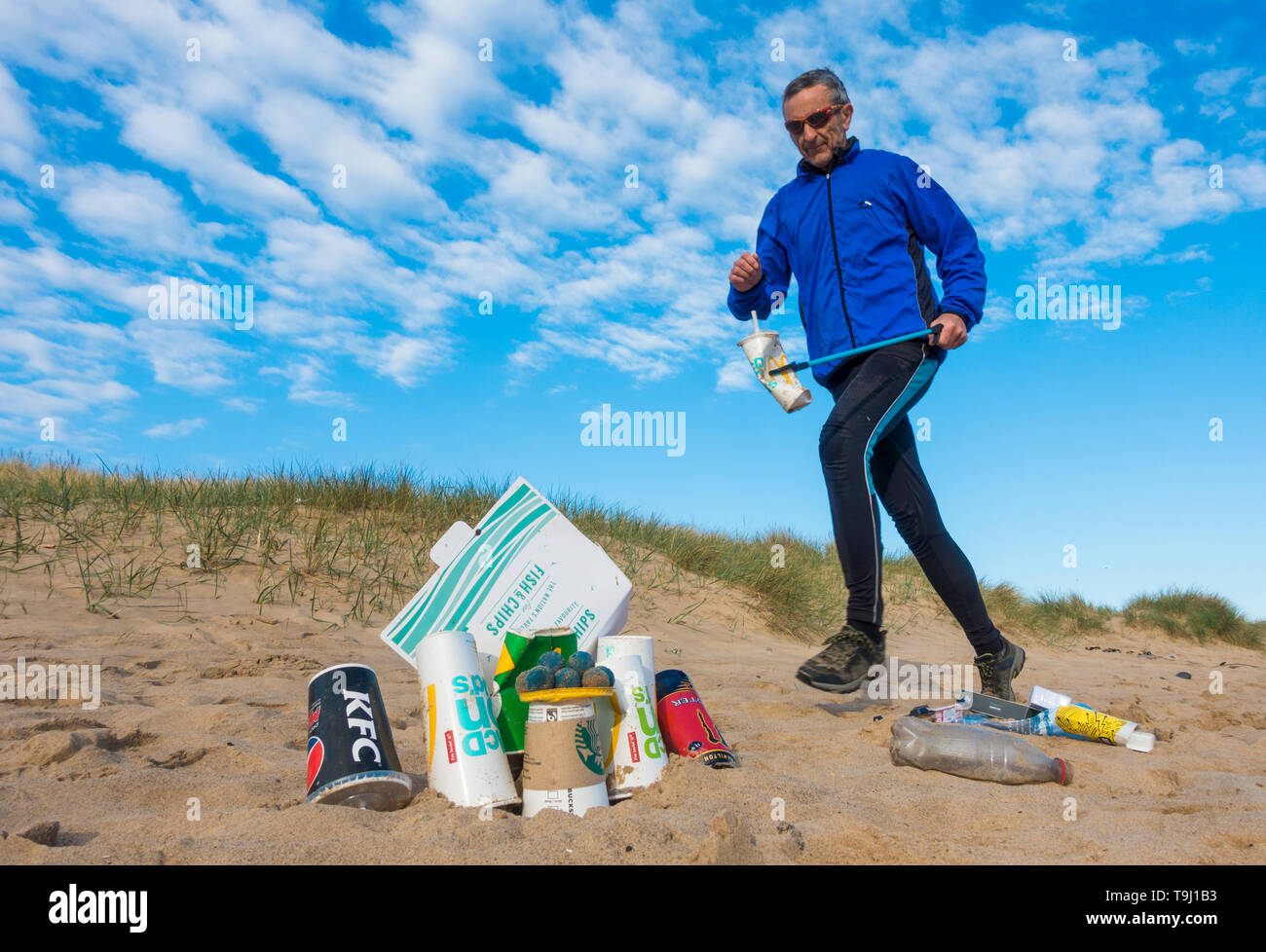 Seaton Carew, County Durham, Regno Unito. Il 19 maggio 2019. Regno Unito: meteo una gloriosa mattina per Plogging. Un pareggiatore raccoglie la spazzatura sulla sua corsa mattutina attraverso le dune a Seaton Carew sulla costa nord est dell'Inghilterra. Plogging (prelievo di lettiera durante il jogging) è un stile di vita scandinavo tendenza dove gli amanti del jogging prelevamento rifiuti/plastica come essi corrono. Credito: Alan Dawson/Alamy Live News Foto Stock