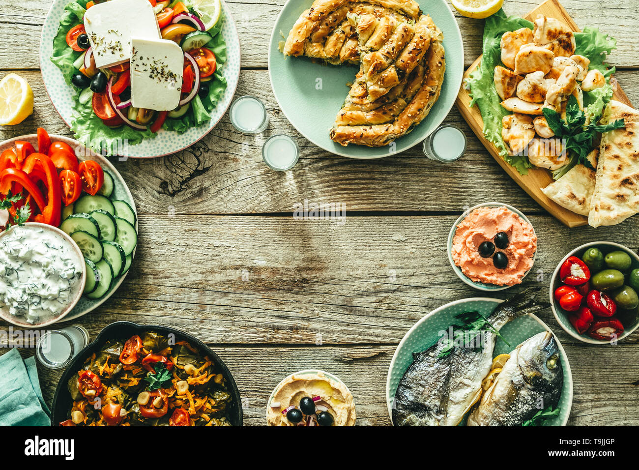 Selezione di piatti greci tradizionali - insalata, meze, torta di pesce, tzatziki, dolma su uno sfondo di legno Foto Stock