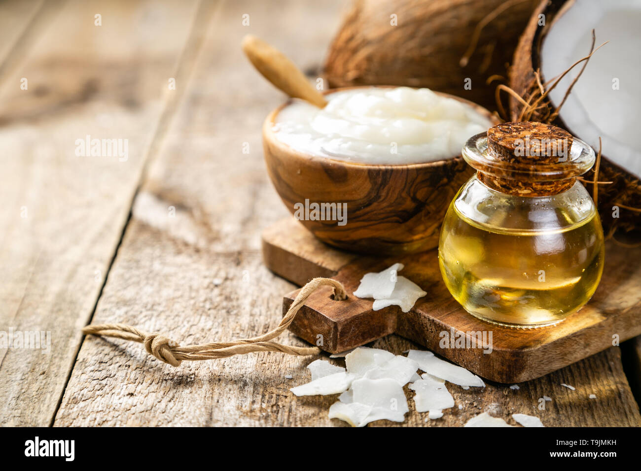 MCT olio di noce di cocco concetto - Noci di cocco, burro e olio su uno sfondo di legno Foto Stock