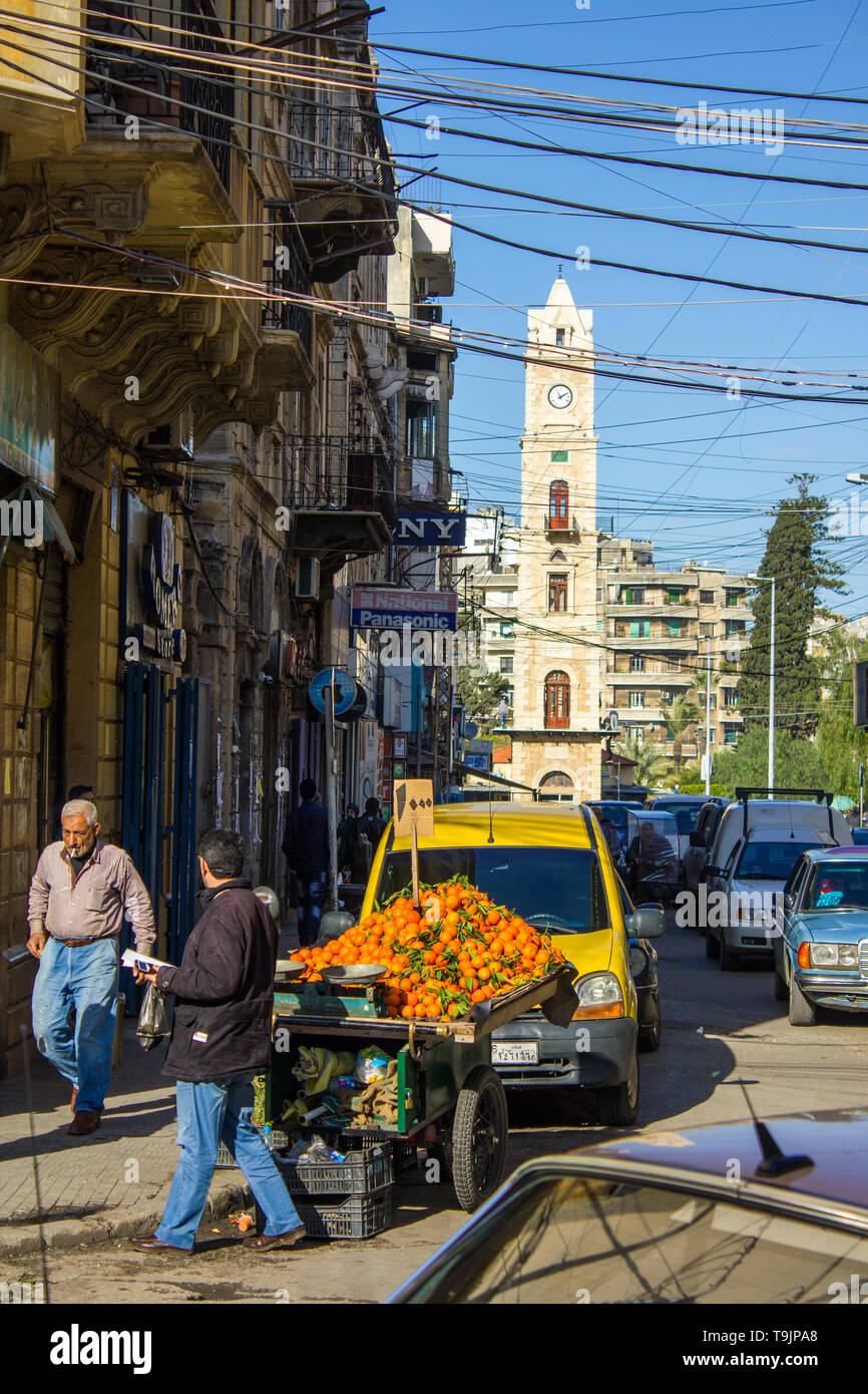Tripoli, Libano - 15 Gennaio 2016: uomo vendere i tangerini nel centro cittadino e la Al-Tell Torre dell Orologio a Tripoli in Libano Foto Stock