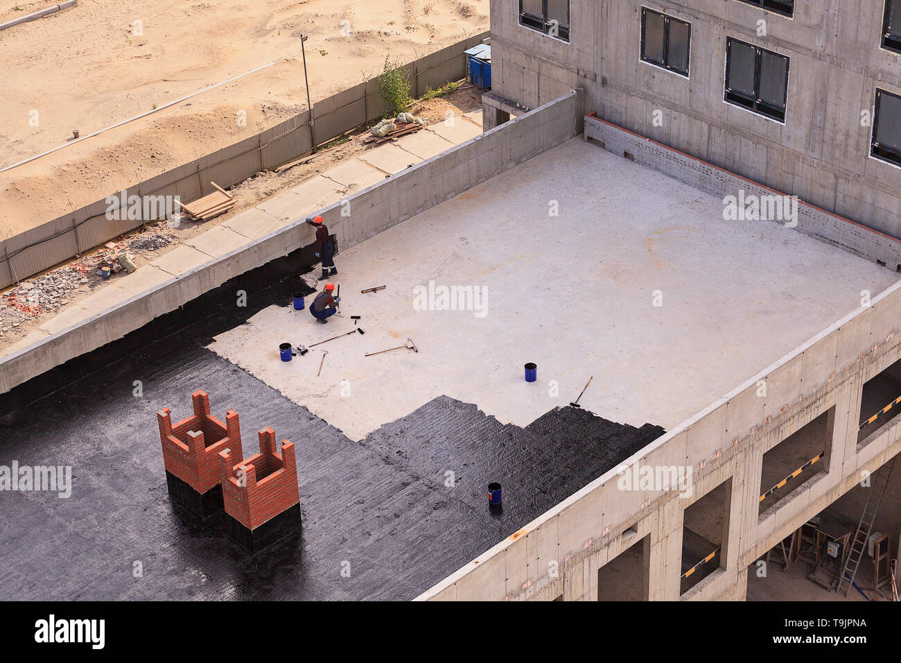 Due lavoratori condurre impermeabilizzazione del tetto con il bitume. Vista da sopra. Foto Stock