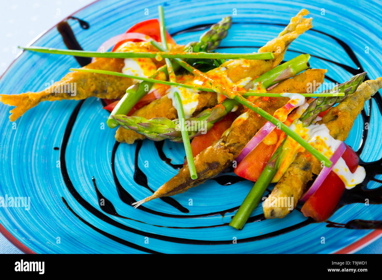 Fritti in pastella spratti con cremosa salsa di zenzero sul cuscino di pomodori dolci, verdi e pasta di aceto balsamico Foto Stock