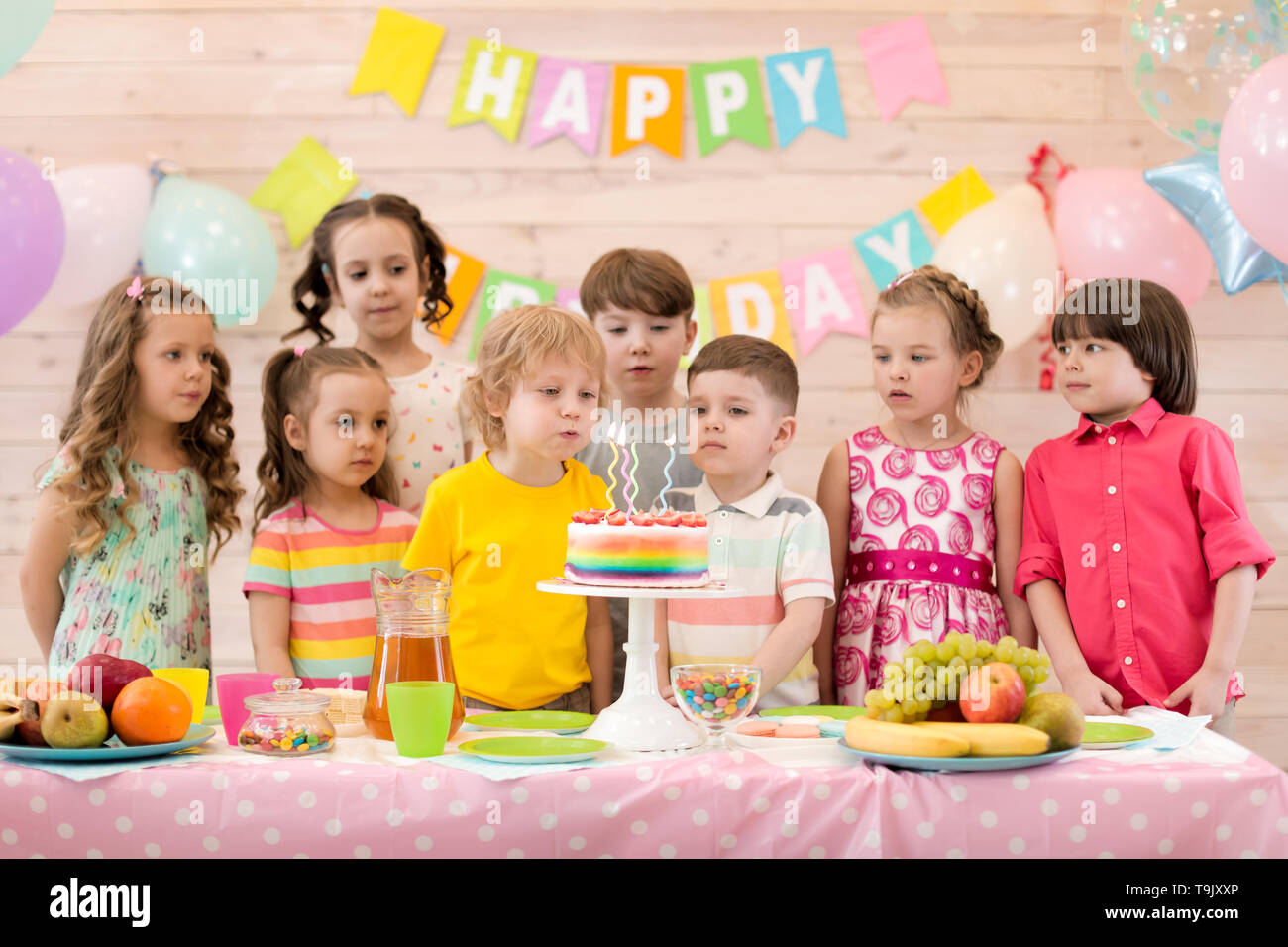 Compleanno boy soffia festival candele sulla torta insieme con i suoi amici Foto Stock