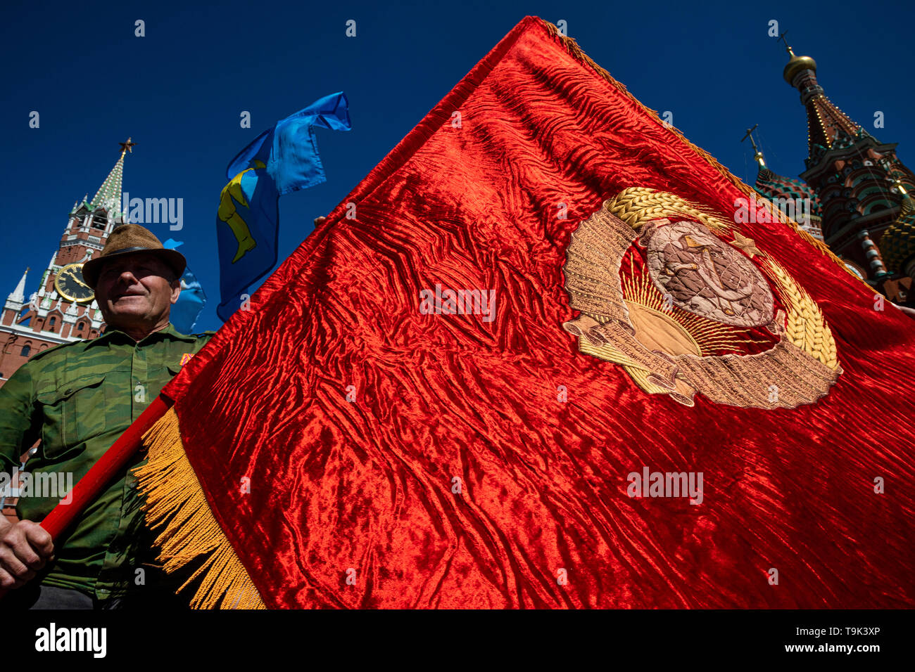 Un uomo in possesso di un banner rosso ricamato con l'emblema dell'URSS sulla Piazza Rossa nel centro di Mosca durante il regime comunista partito del rally, Russia Foto Stock