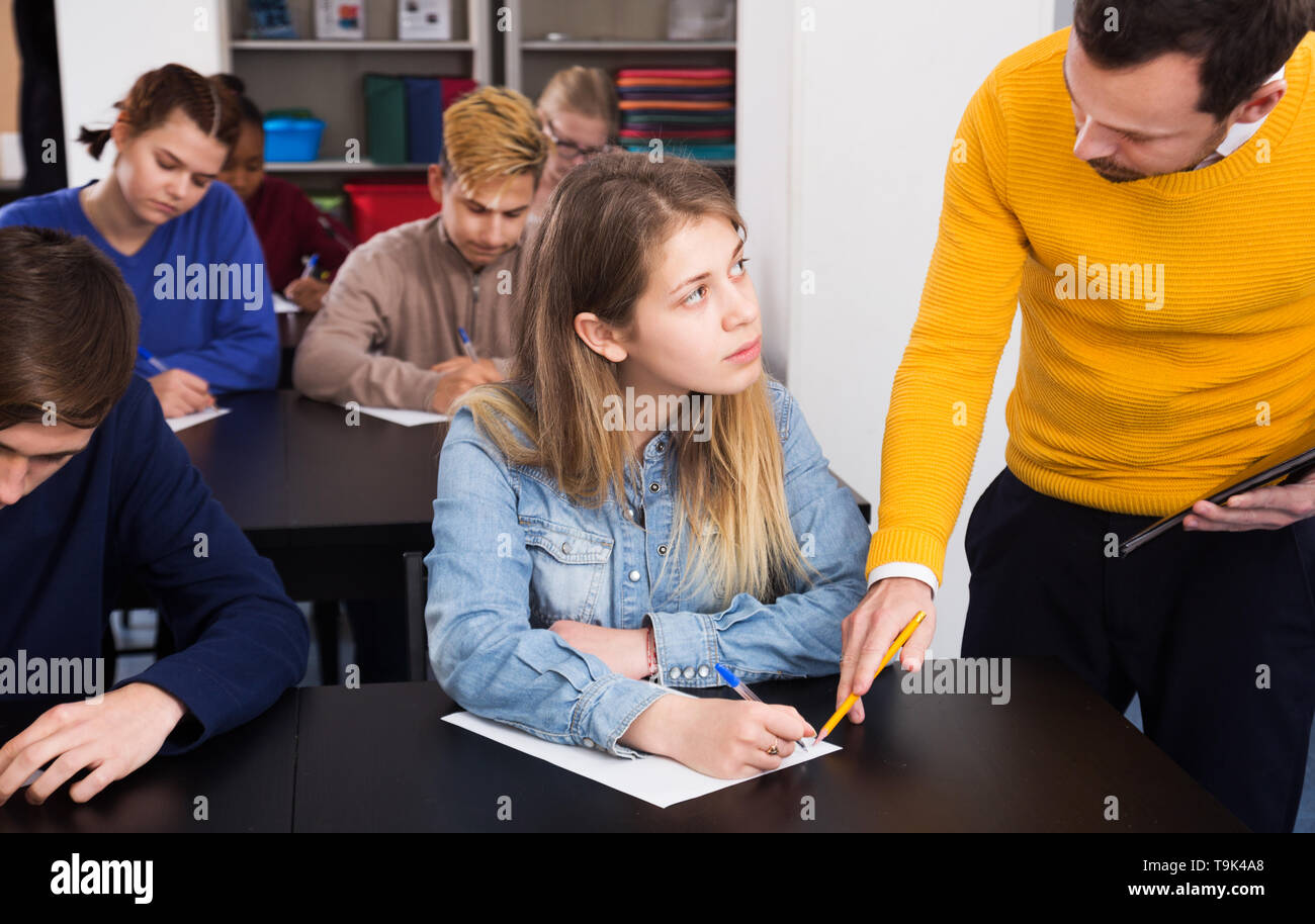 Insegnante di grave dare spiegazione agli studenti durante il lavoro di revisione in classe Foto Stock