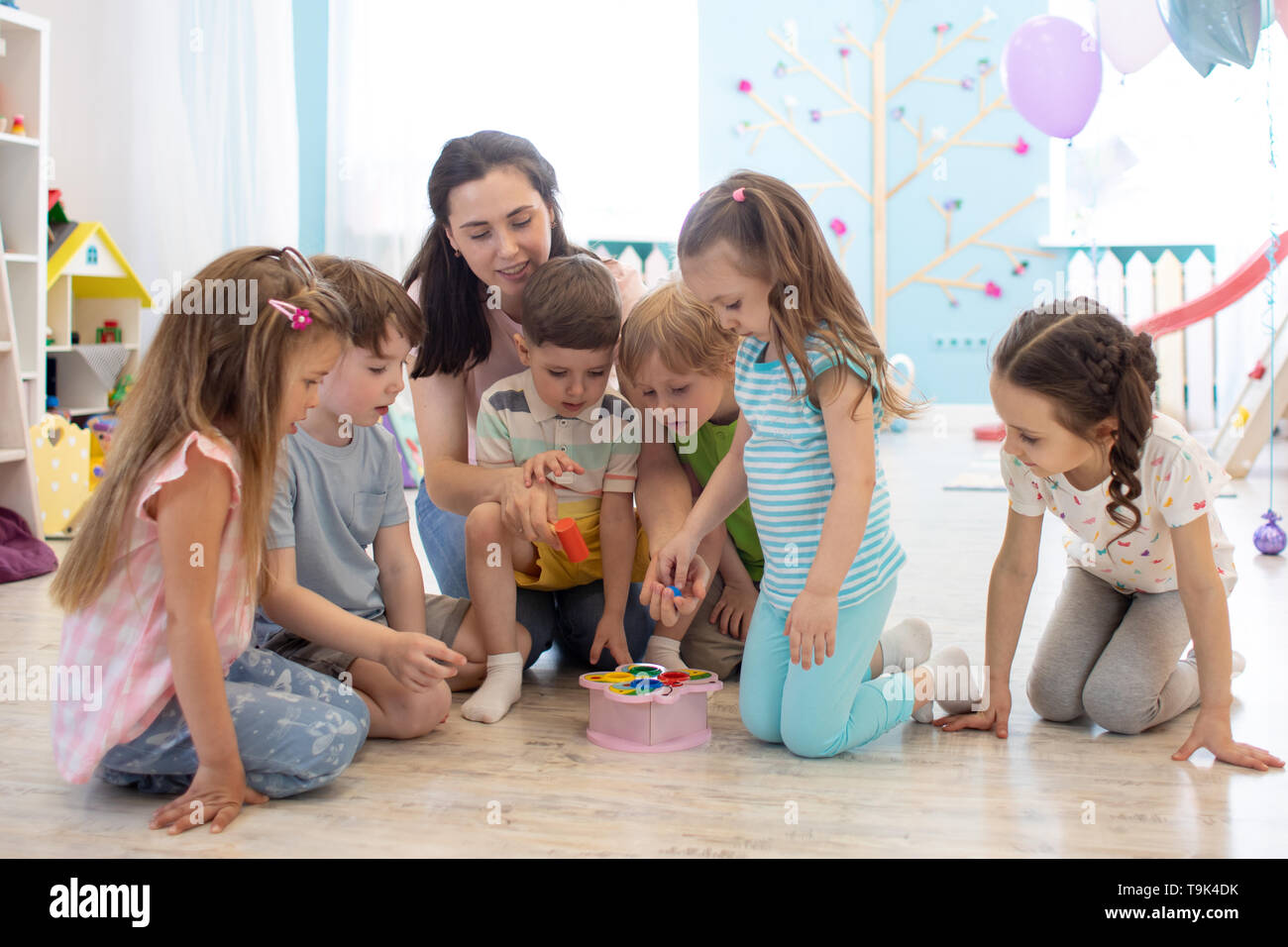 Insegnante femmina insegnare ai ragazzi giocare giocattolo in aula. Kindergarten concetto in età prescolare Foto Stock