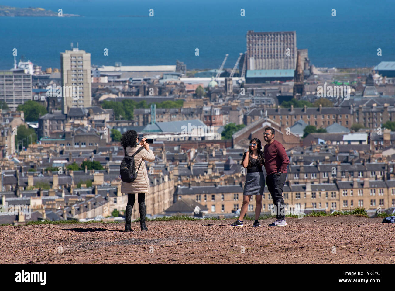 I turisti hanno la loro fotografia scattata su Calton Hill con Leith in background. Foto Stock