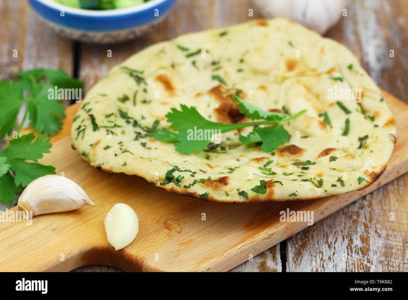 Appena sfornati Indian nan pane con il coriandolo fresco e aglio sul pannello di legno Foto Stock