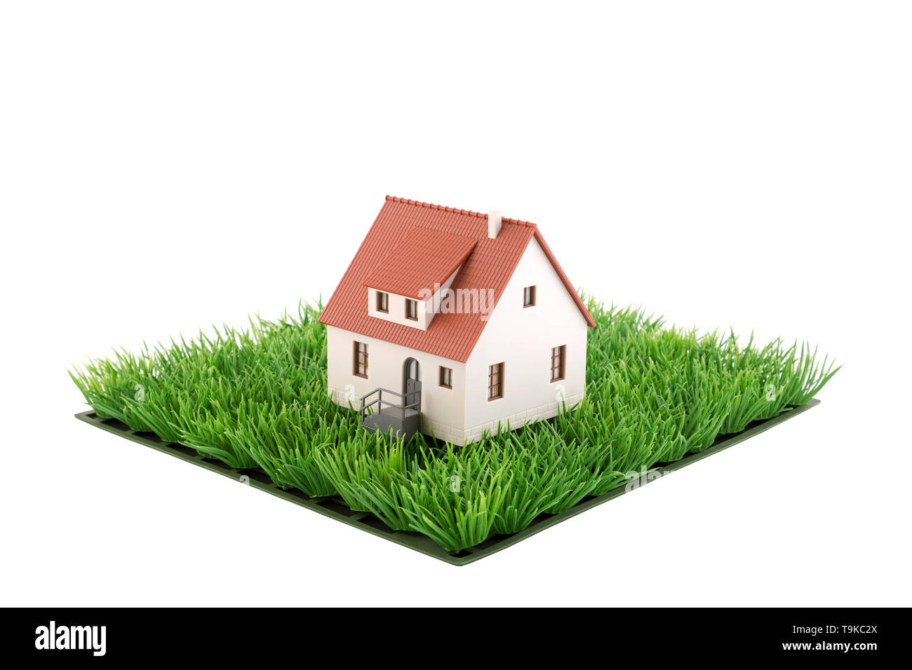 Casa miniatura su piazza di erba verde campo isolato su sfondo bianco Foto Stock