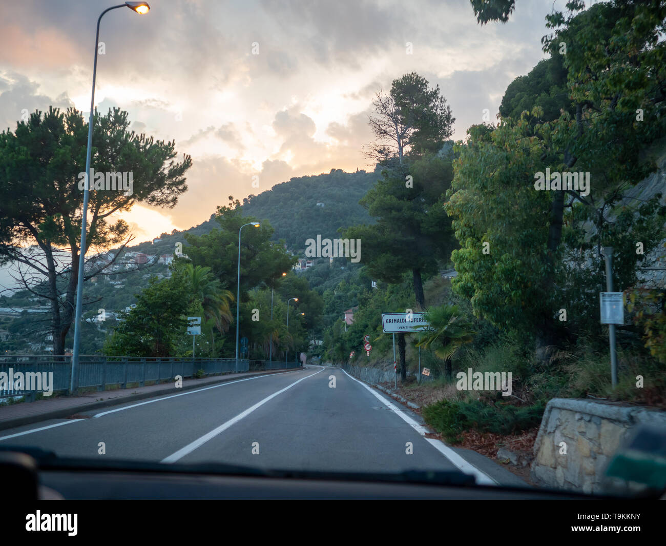 Strada costiera al confine della Riviera francese e italiana di entrare nella piccola città di Grimaldi al tramonto Foto Stock