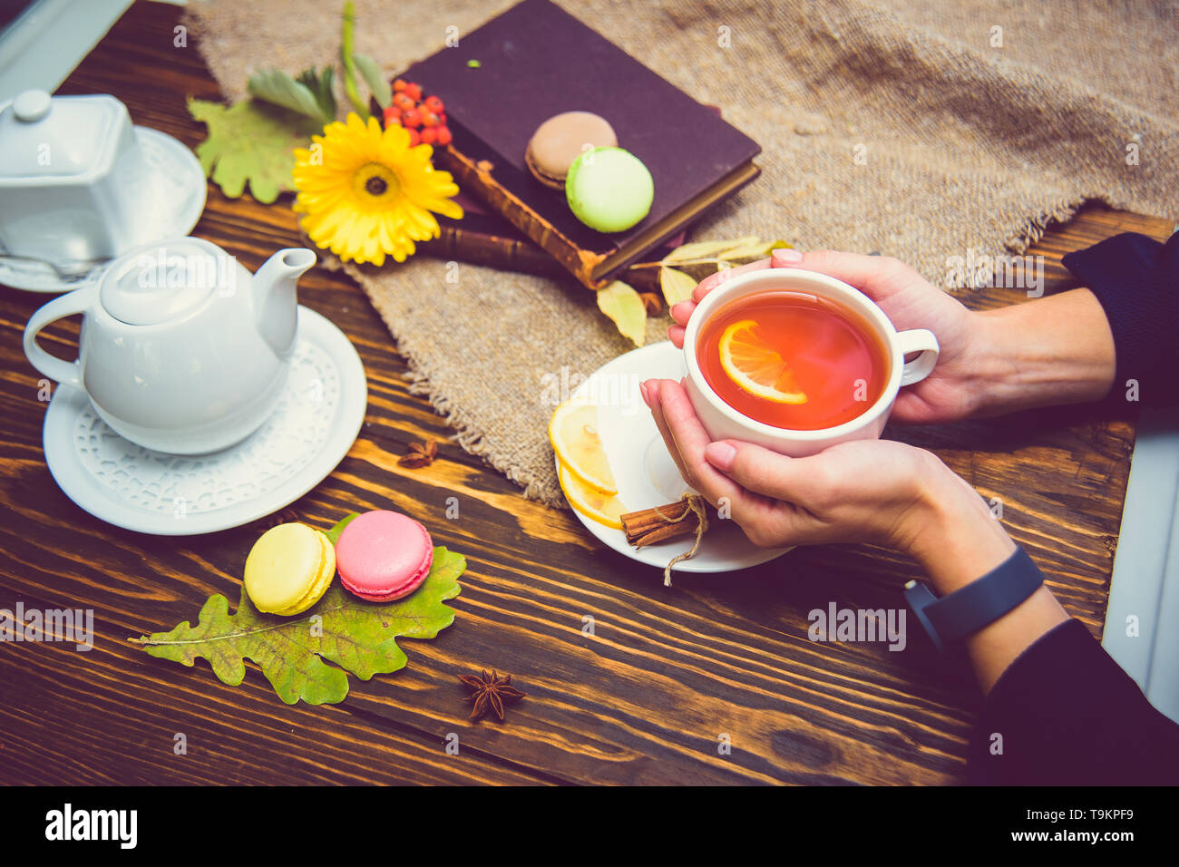 Una tazza di tè nero con limone riscalda i palmi della ragazza. In Coppa le palme Foto Stock