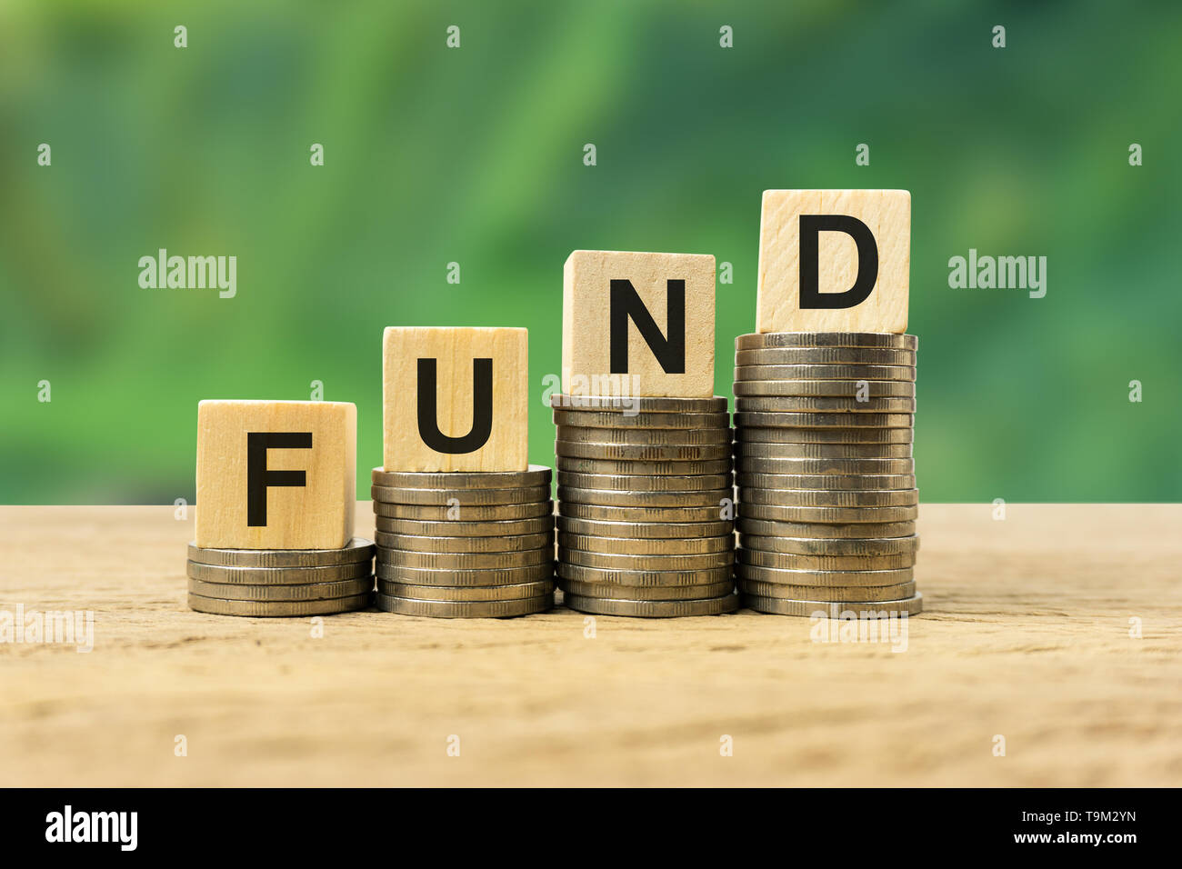 Concetto di investimento a lungo termine di fondi. Blocco di legno sulla pila in formazione monete sul tavolo di legno. La illustra la stabilità, ricchezza, investimento sicuro a lungo termine. Foto Stock