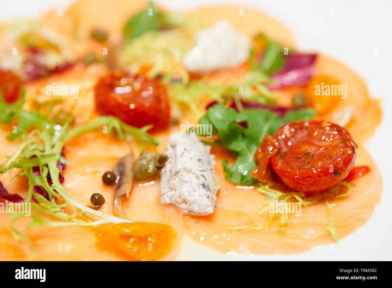 Carpaccio di salmone con salsa e sole asciugato i pomodori in piastra, close-up shot Foto Stock