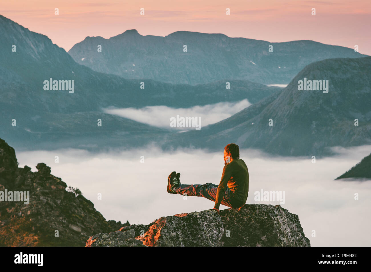 Uomo sportivo di formazione sulla scogliera di montagna sopra le nuvole da soli viaggiare sano stile di vita viaggio d avventura le vacanze all aria aperta Foto Stock