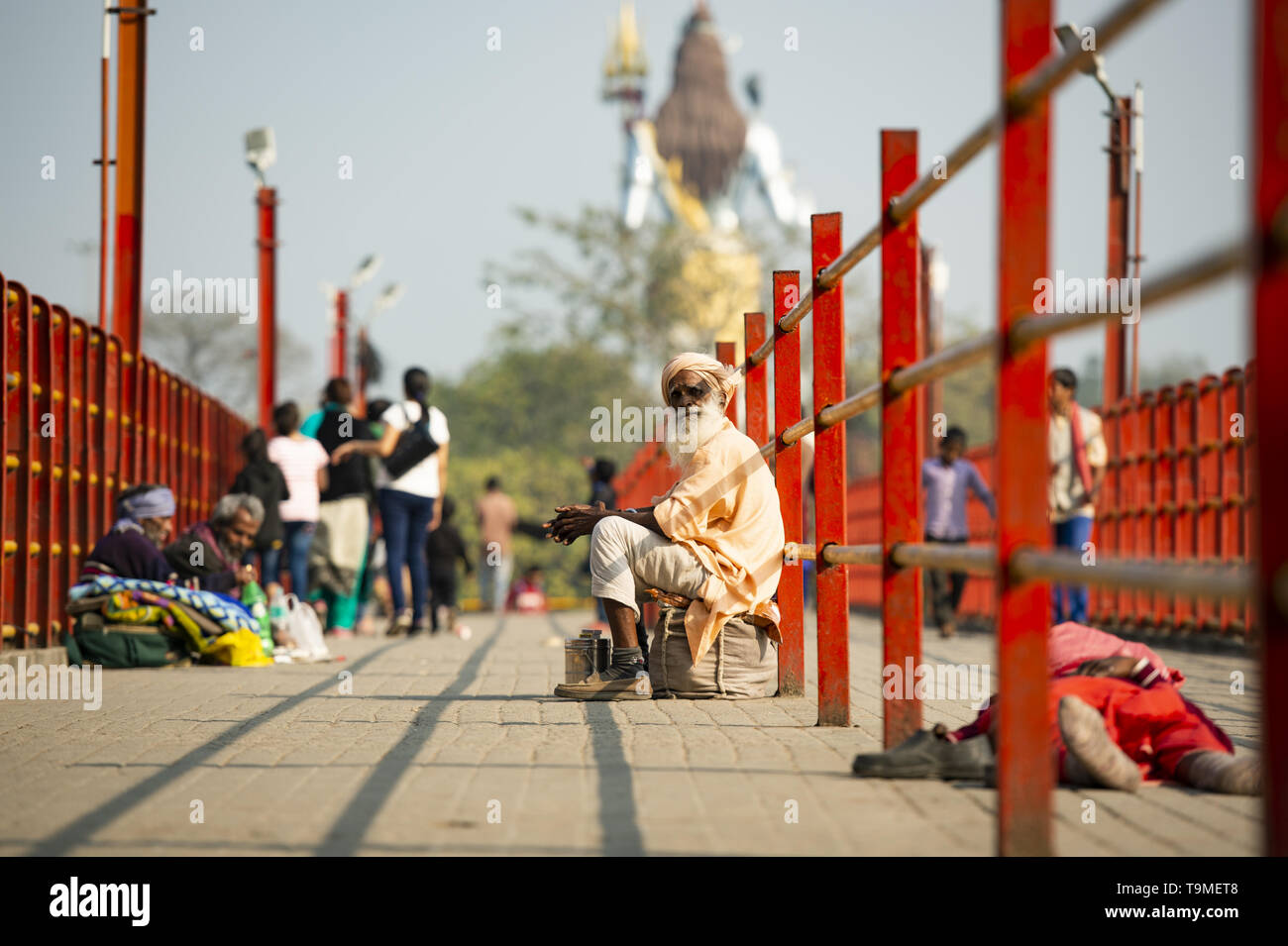 Un povero Sadhu è chiedere denaro in Haridwar, India. Sfumata del signore Shiva in background. Foto Stock