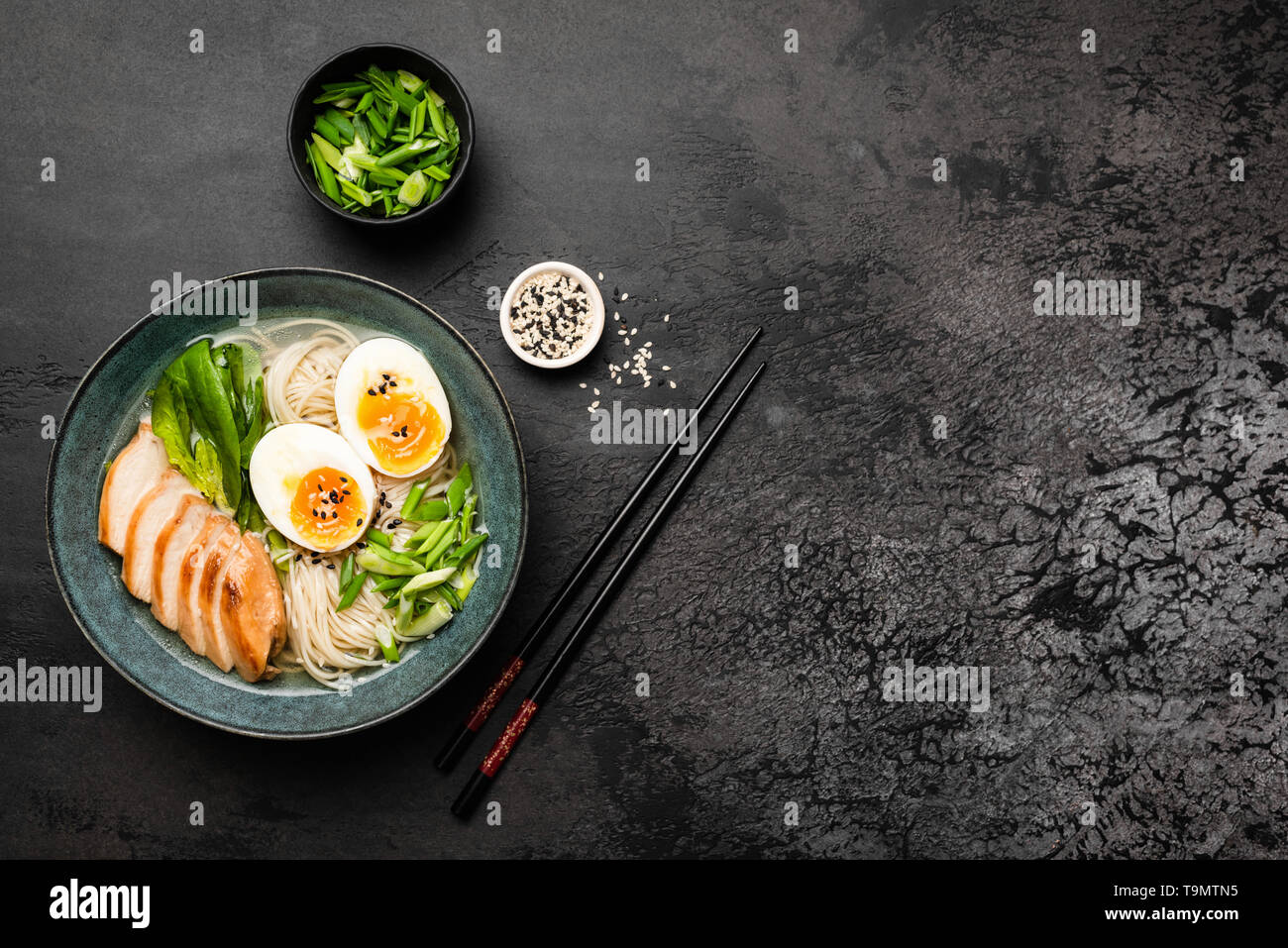 Ramen con pollo e uovo nero su sfondo di calcestruzzo. Vista dall'alto. Copia spazio per il testo. Cucina asiatica food Foto Stock
