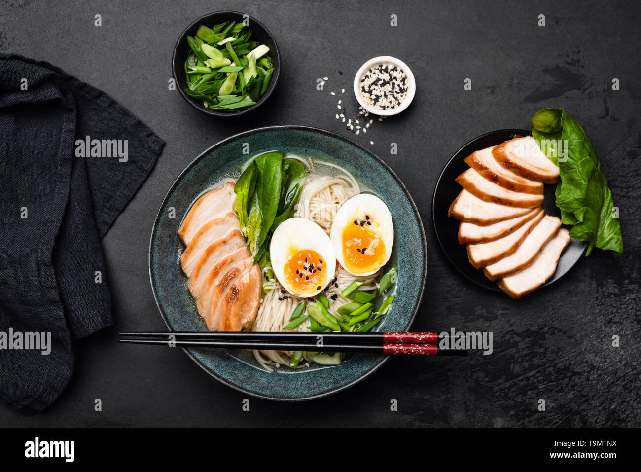 Giapponese ramen noodle soup bowl sulla pietra nera dello sfondo. Tabella vista superiore di cucina asiatica food. Foto Stock