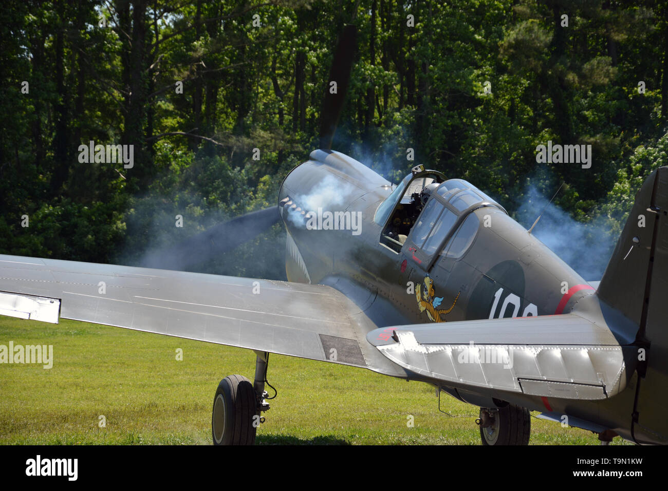 Colpi di fumo dal motore di un Curtiss P-40 Warhawk con battenti Tiger insegna come si prepara per il decollo durante la seconda guerra mondiale air show in Virginia Beach VA Foto Stock