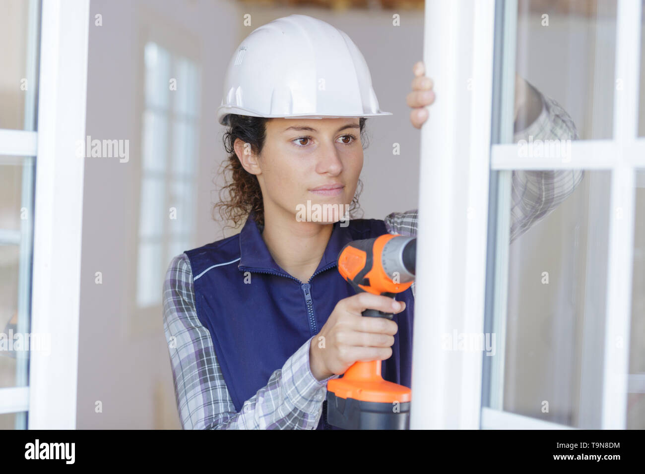 Donna laboriosa operazione di foratura di una finestra Foto Stock