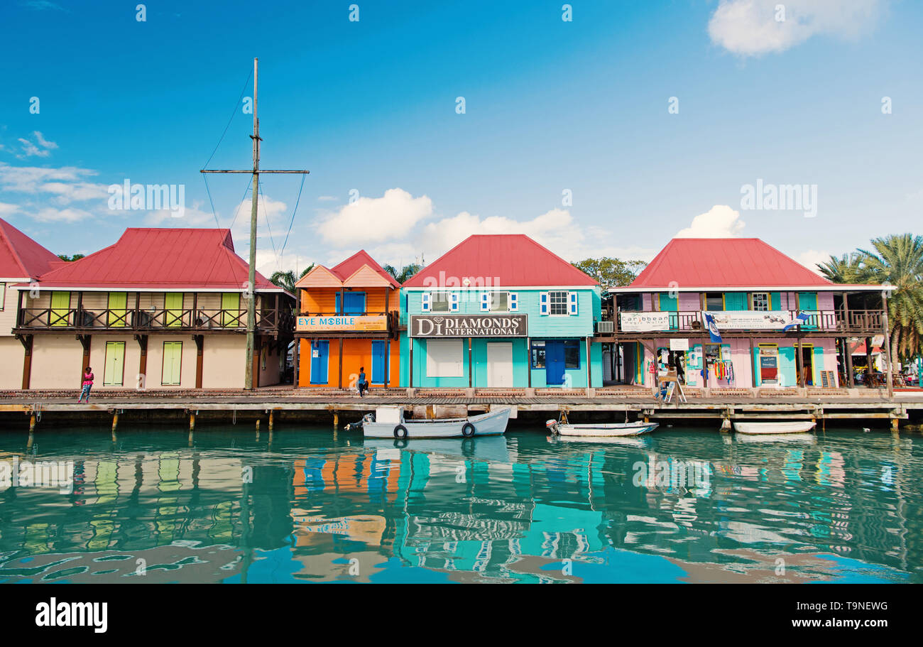 St Johns, Antigua - Marzo 05, 2016: barche ormeggiate in mare al molo del villaggio con case a cielo blu. Vacanze estive sull isola tropicale. Scoperta e adv Foto Stock
