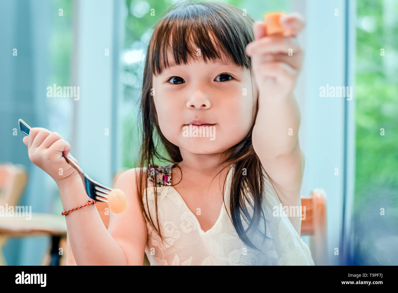 Piccolo bambino asiatico ragazza avente la prima colazione al mattino con un felice volto sorridente Foto Stock
