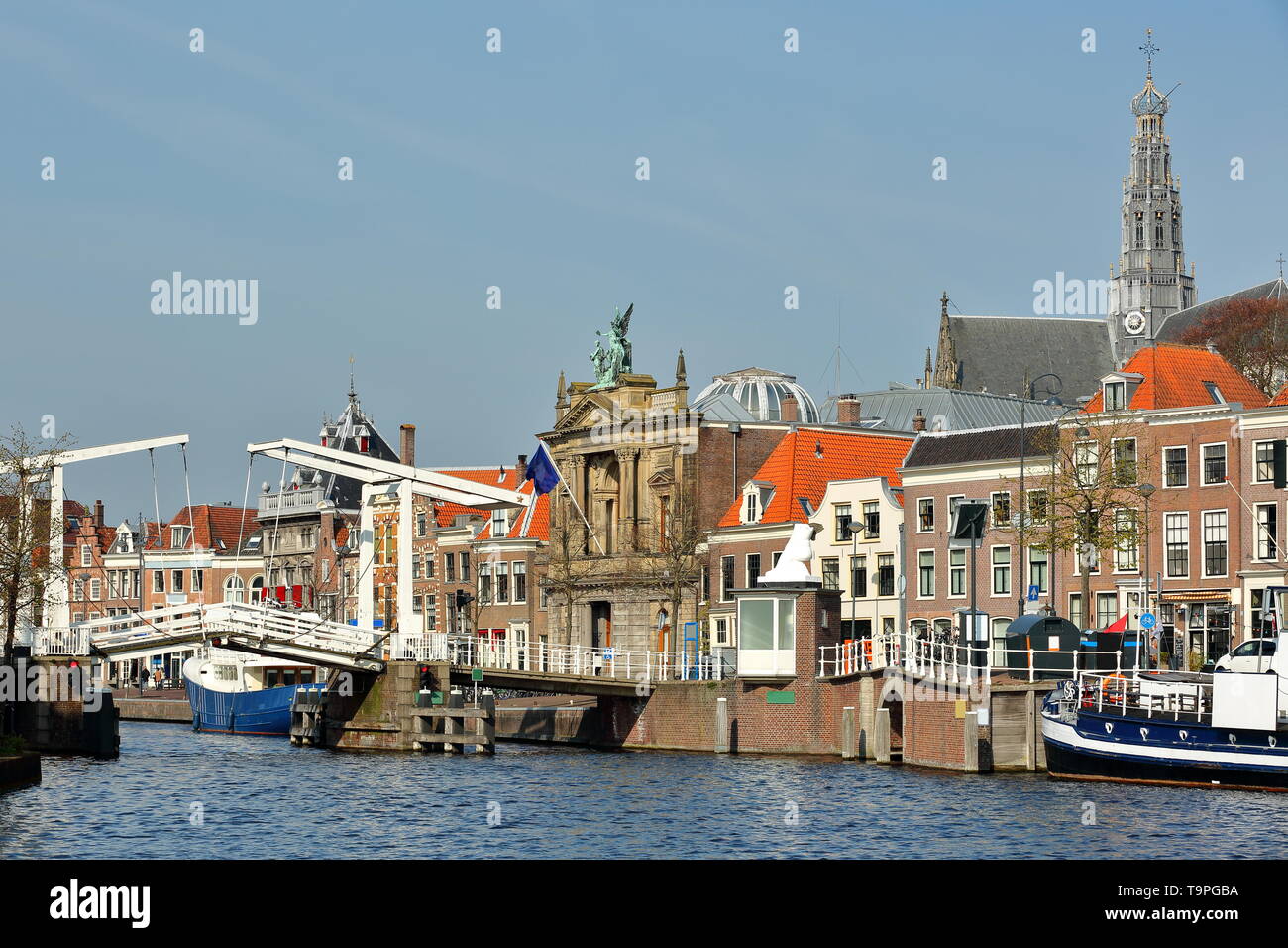 La Spaarne riverside, con Teylers Museum, Gravestenenbrug bridge e la torre dell orologio di St Bavokerk chiesa in background, Haarlem, Paesi Bassi Foto Stock