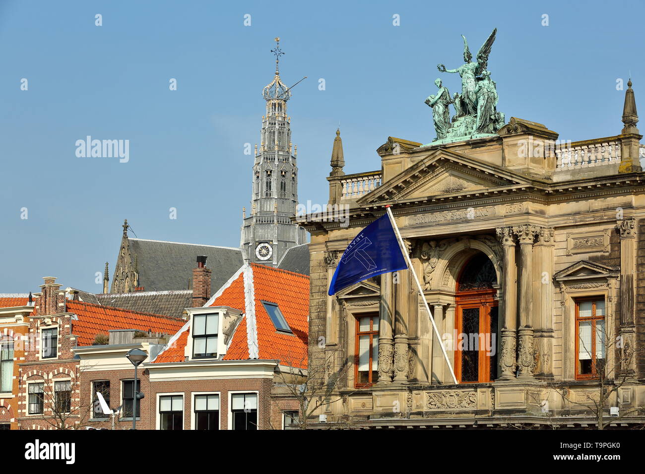 La facciata esterna del Teylers Museum, situato lungo il fiume Spaarne, con la torre dell orologio di St Bavokerk chiesa in background, Haarlem, Paesi Bassi Foto Stock