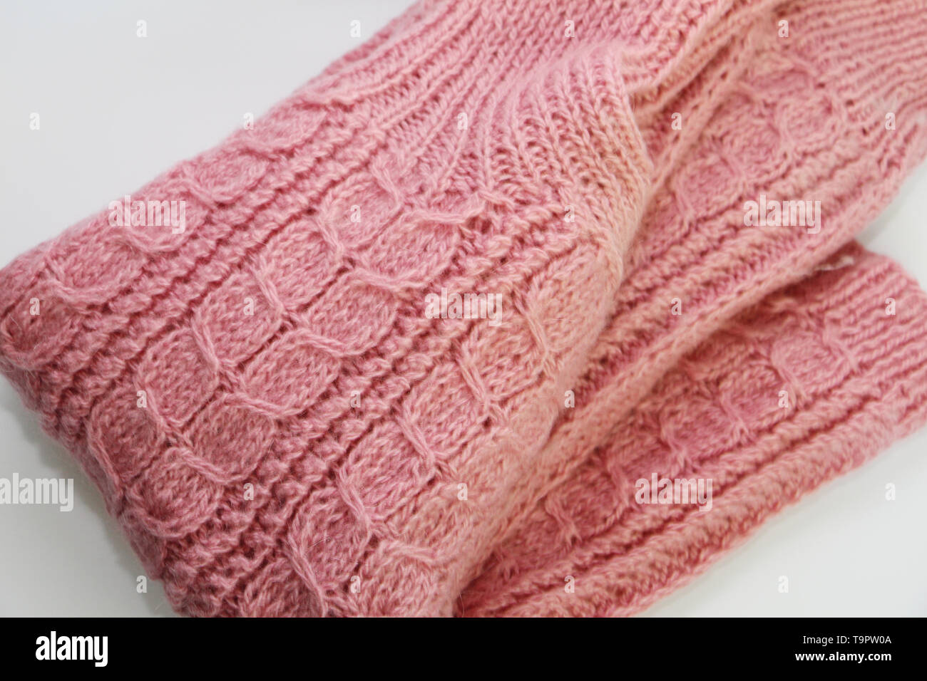 Un caldo colore rosa felpa lavorata a maglia è sdraiato su uno sfondo bianco. Un bel disegno è visibile su il maglione. Modello unico di close-up. Maglione è complic Foto Stock