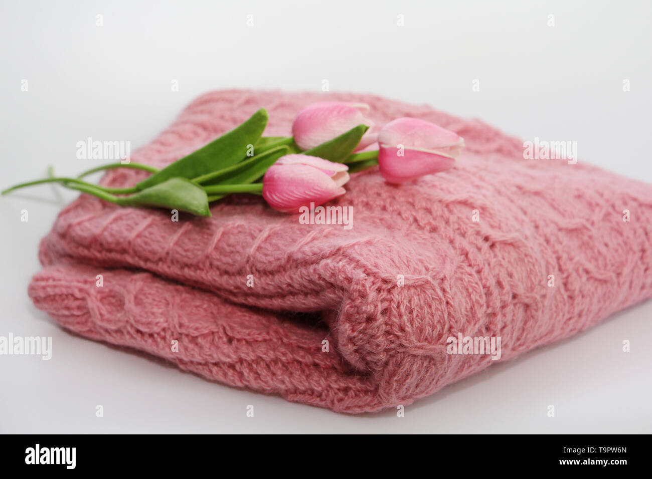Un caldo colore rosa felpa lavorata a maglia è sdraiato su uno sfondo bianco. Il maglione è visibile la tessitura di un bel disegno. Maglione è complicato. Sulla s Foto Stock