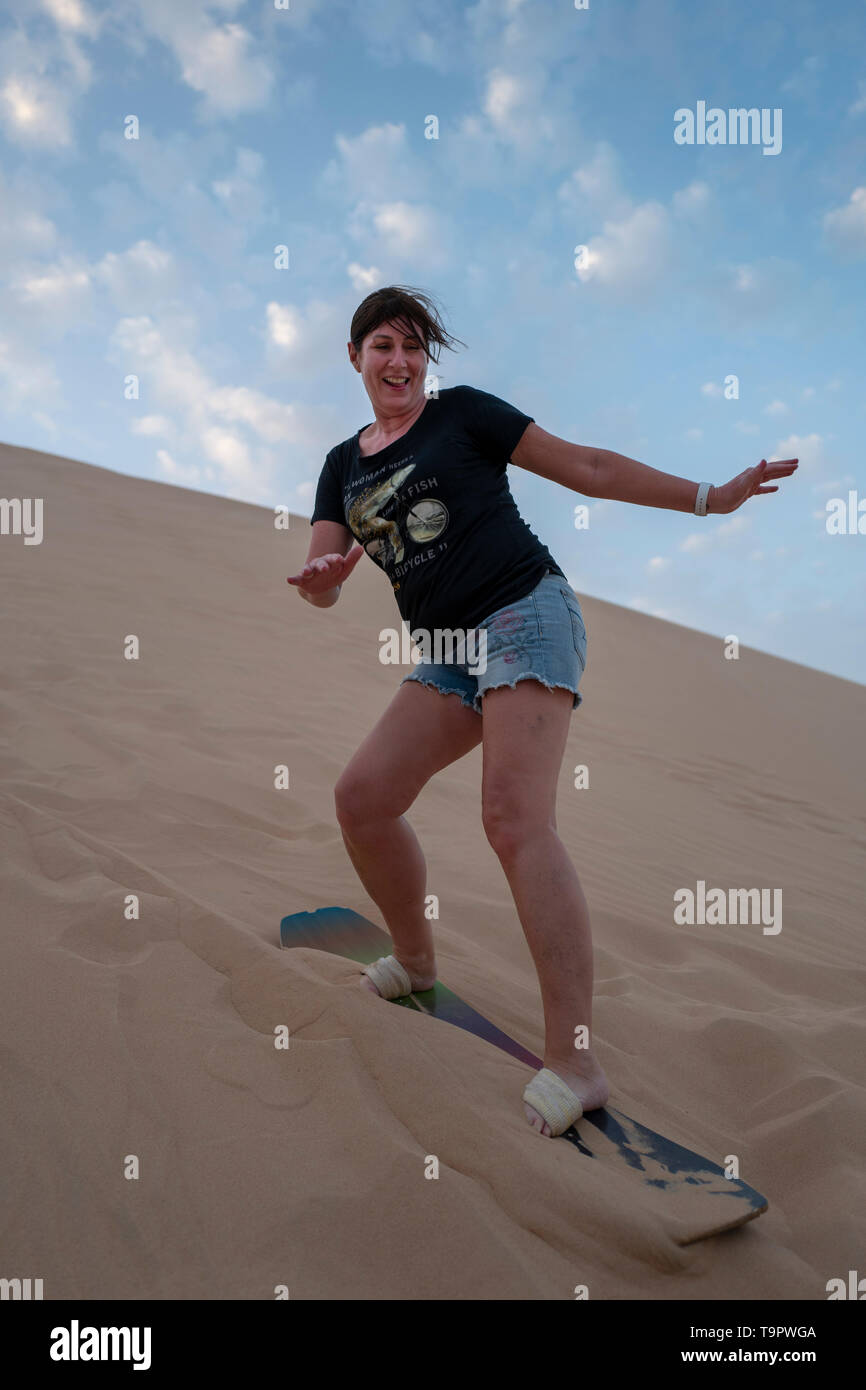 I turisti in Abu Dhabi provate sand boarding sulle dune del deserto degli EMIRATI ARABI UNITI Foto Stock