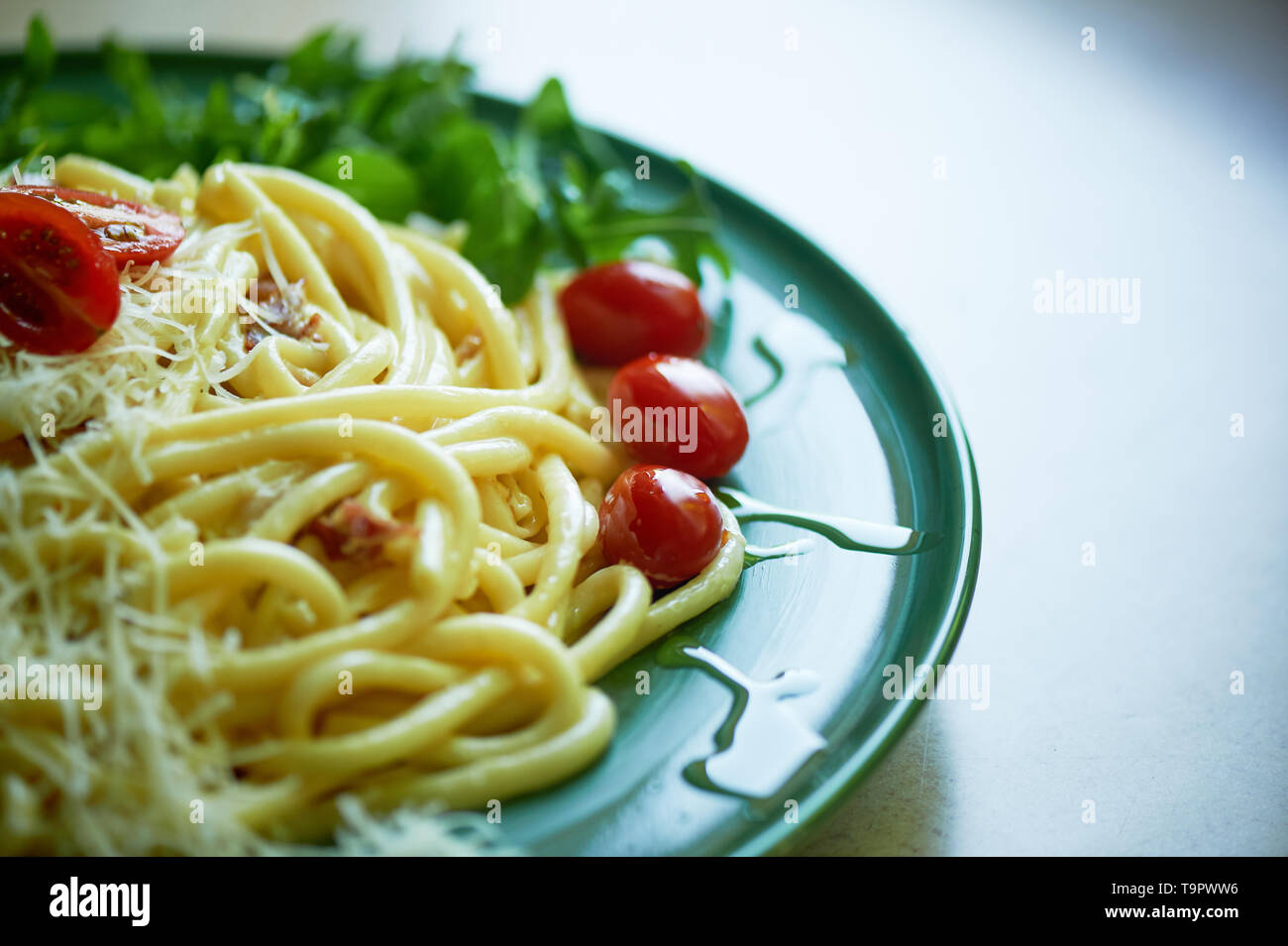 La pasta alla carbonara con parmigiano grattugiato e pomodorini, decorato con foglie di rucola.Italiano per pranzo. Foto Stock