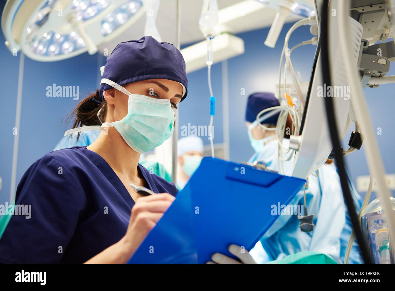 Infermiera femmina esaminando tutti i parametri in sala operatoria Foto Stock