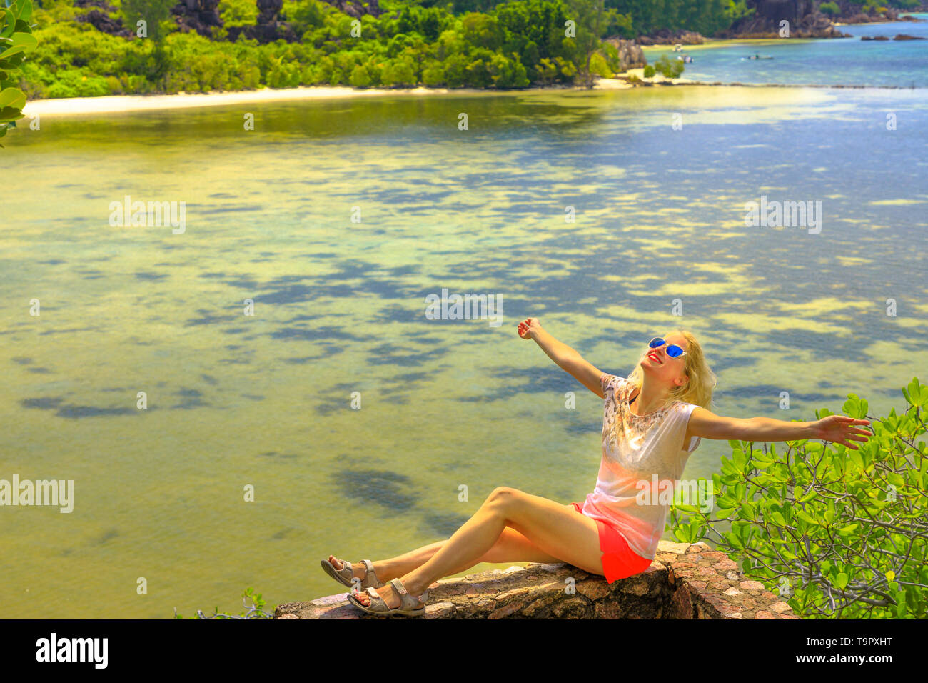 Donna turistica godendo a si affacciano sopra la baia Laraie e acque turchesi dell'Oceano Indiano in Curieuse, Isole Seychelles. Vista dall'alto lungo Foto Stock