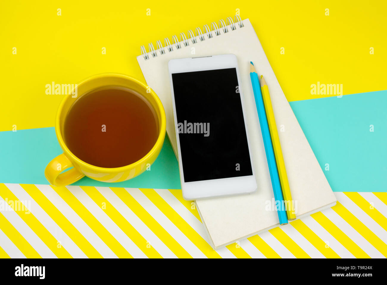 Vista dall'alto per notebook vuoto con foglio di carta bianco, smartphone,matite e la tazza di tè Foto Stock